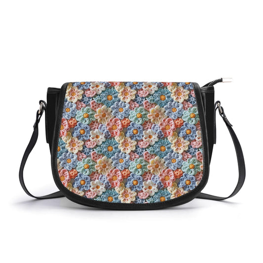 The Posy' Pock-It Saddle Handbag showcases colorful flower petals in a crochet look, with a sleek clasp and adjustable strap