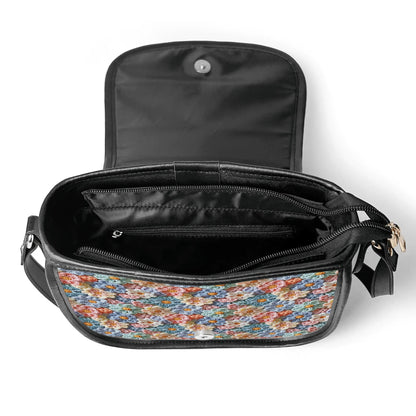 The Posy' Pock-It Saddle Handbag showcases colorful flower petals in a crochet look, with a sleek clasp and adjustable strap