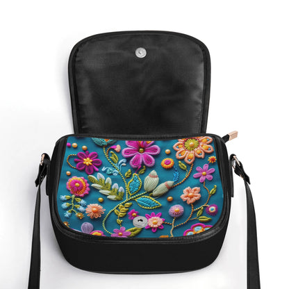 "Pock-It Saddle Handbag - Petal Pop by ShitHot features colorful flower print, secure zipper, and adjustable strap."