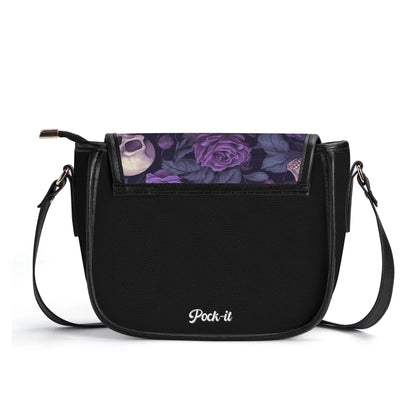 "Gothic Garden saddle handbag with skulls and purple flowers, secure closure, and adjustable strap."