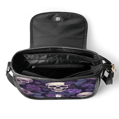 "Gothic Garden saddle handbag with skulls and purple flowers, secure closure, and adjustable strap."