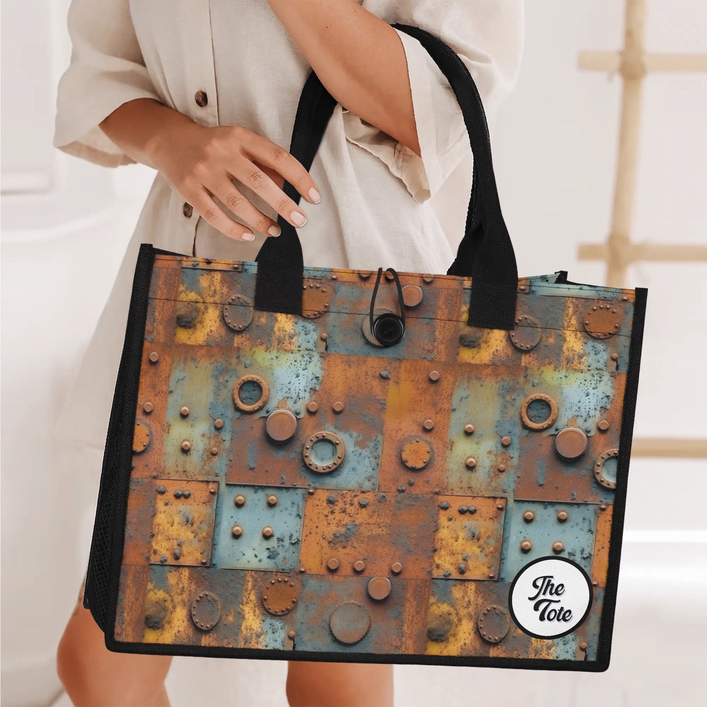 "The Tote Bag - Metal Head features oxidized panels and metal accents, available in two sizes for stylish functionality."