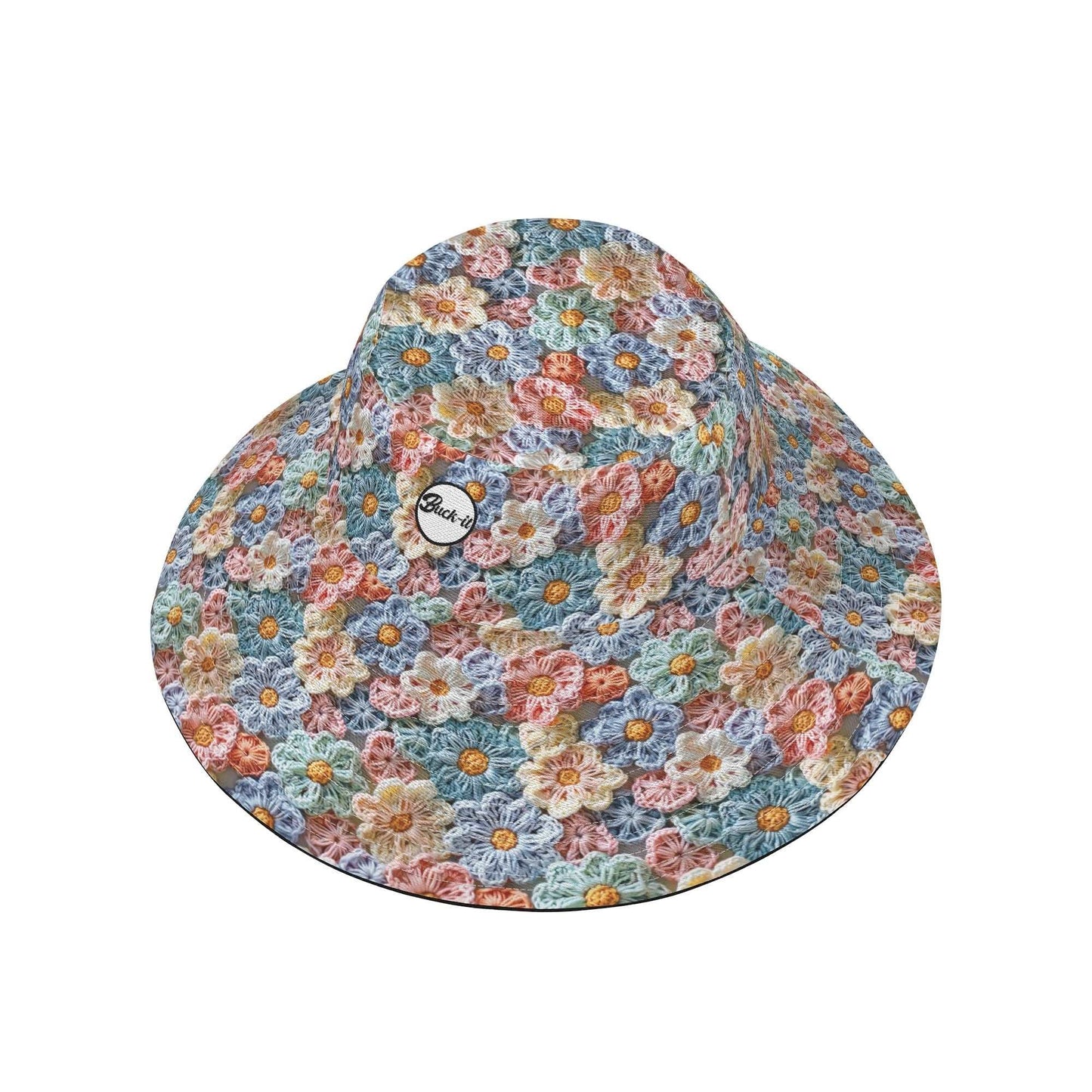 The Posy Bucket Hat featuring a vibrant crochet floral pattern in pastel blue, pink, and beige tones, with a small circular brand logo on the side. The hat displays a classic bucket shape with an all-over delicate flower petal design.