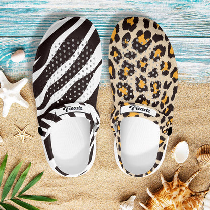 Treadz Mismatch Clogs - Safari featuring mismatched zebra and leopard prints displayed on beach sand with seashells and tropical decor, showcasing unique animal print patterns and comfortable design