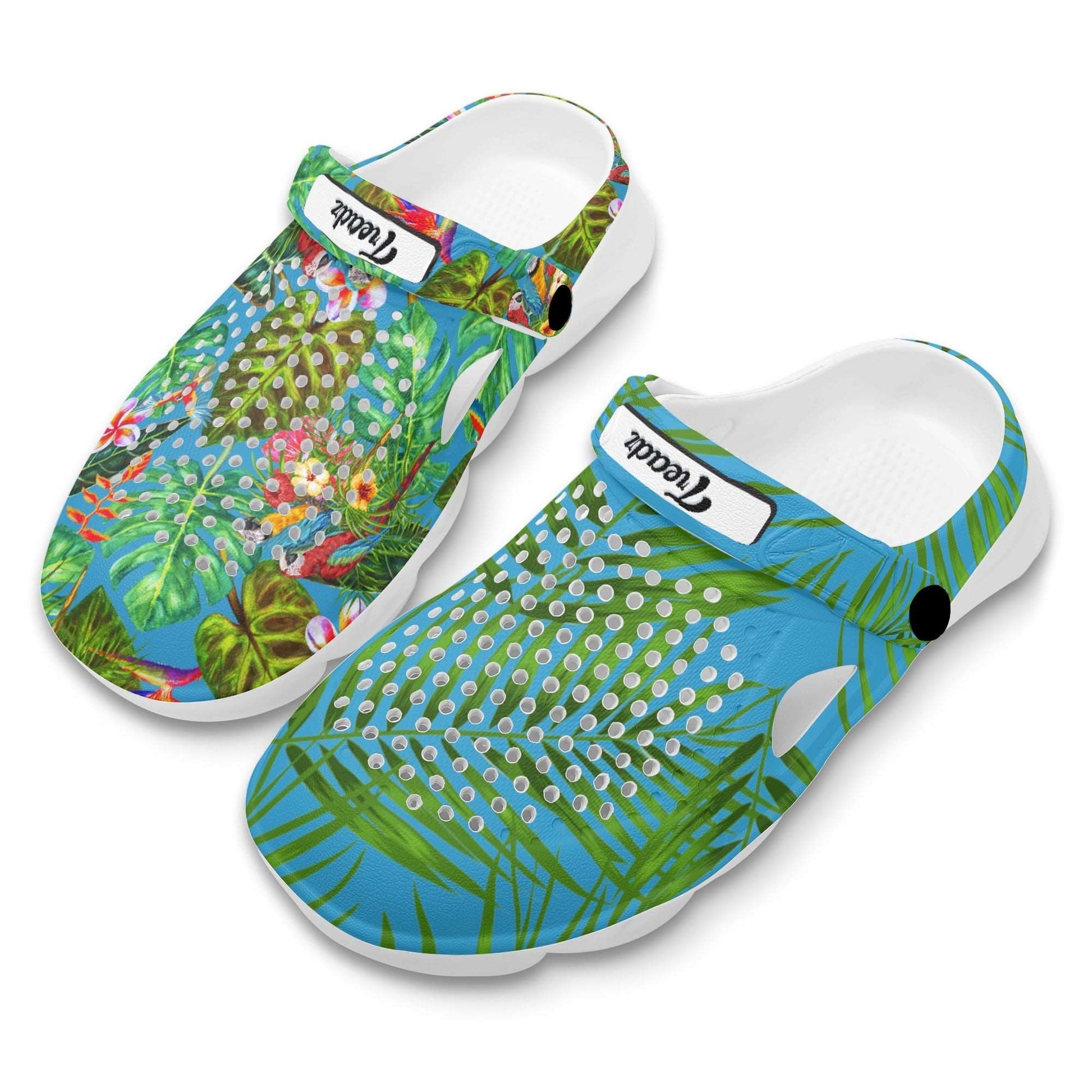 Treadz Mismatch Clogs - Tropicana featuring vibrant tropical design with green palm leaves, colorful birds, and ventilation holes on white EVA material, displaying contrasting patterns between left and right clogs