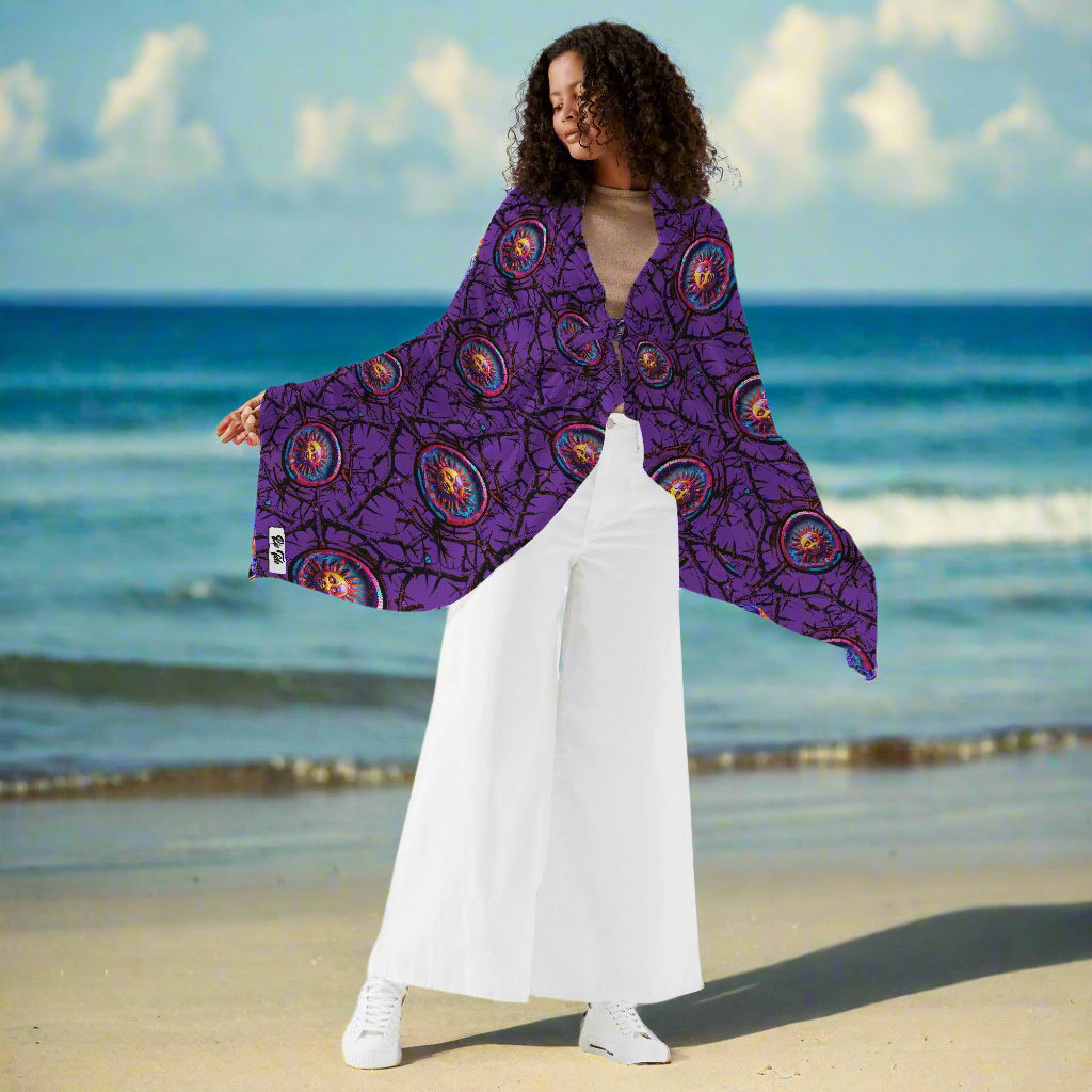 Purple Luna Anarchy sarong displayed as a stylish wrap, featuring vibrant circular patterns on purple background, shown with white palazzo pants to demonstrate versatile beach cover-up styling options