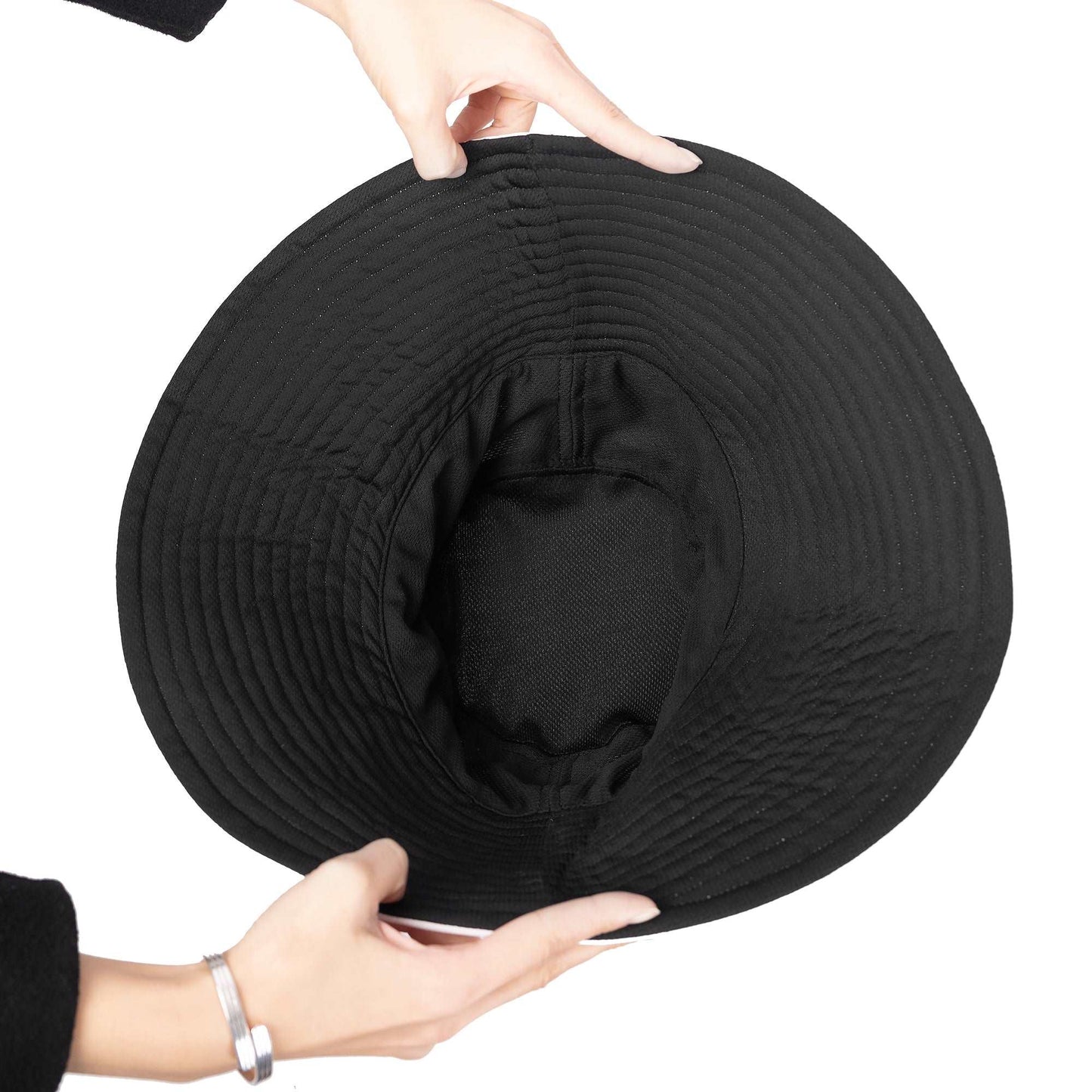 Thunder Camo Bucket Hat shown from above, hands demonstrating its flexible and foldable nature. Black wide-brimmed bucket hat with circular stitching pattern and breathable mesh interior, displaying the hat's packable design and durable construction.