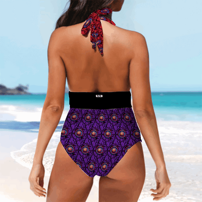 Luna Anarchy Mismatched Tankini Halterneck swimsuit featuring a vibrant purple peacock feather pattern, high-waisted design with black waistband, and red-blue patterned halter tie at neck, photographed from back view on beach setting with turquoise ocean background.