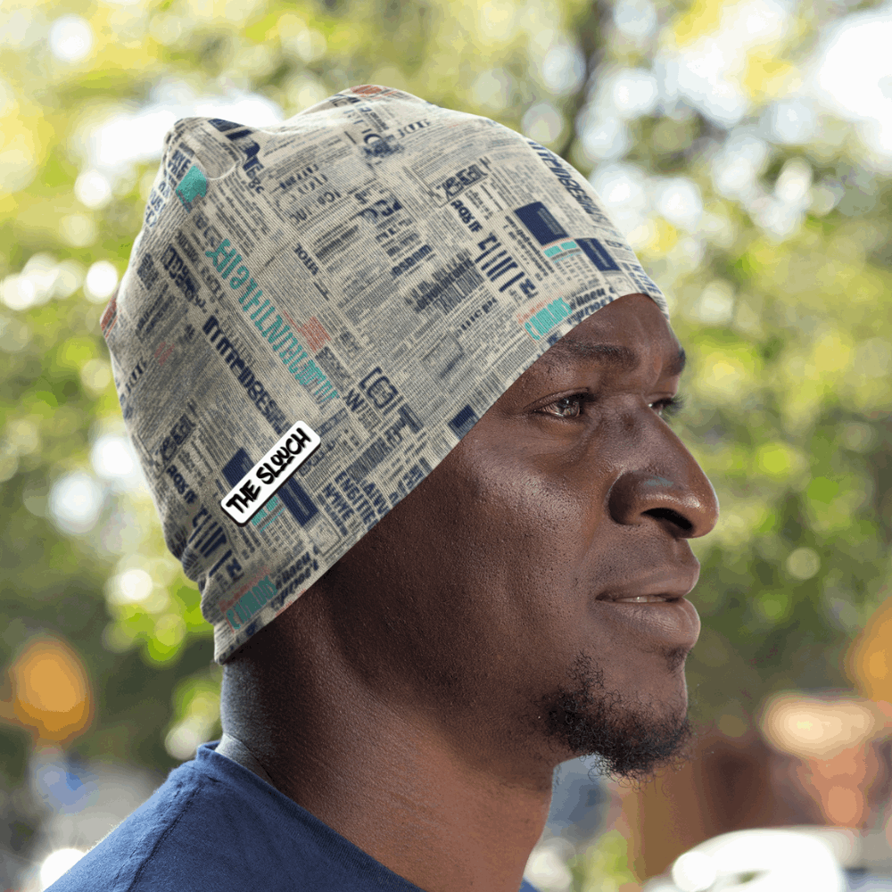 Men's Skull Cap Beanie - Retro News design features a stylish newspaper print pattern in grey and teal tones, shown against a natural outdoor background. The beanie displays a snug, form-fitting design perfect for casual wear and outdoor activities.