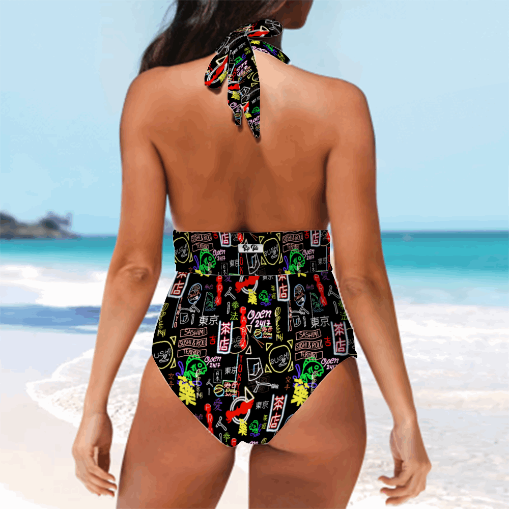 Akihabara Pulse One Piece Tankini shown from back view on beach backdrop, featuring vibrant neon-inspired print with Japanese motifs on black background, halter neck tie design, high-cut silhouette against turquoise ocean and white sand beach setting.