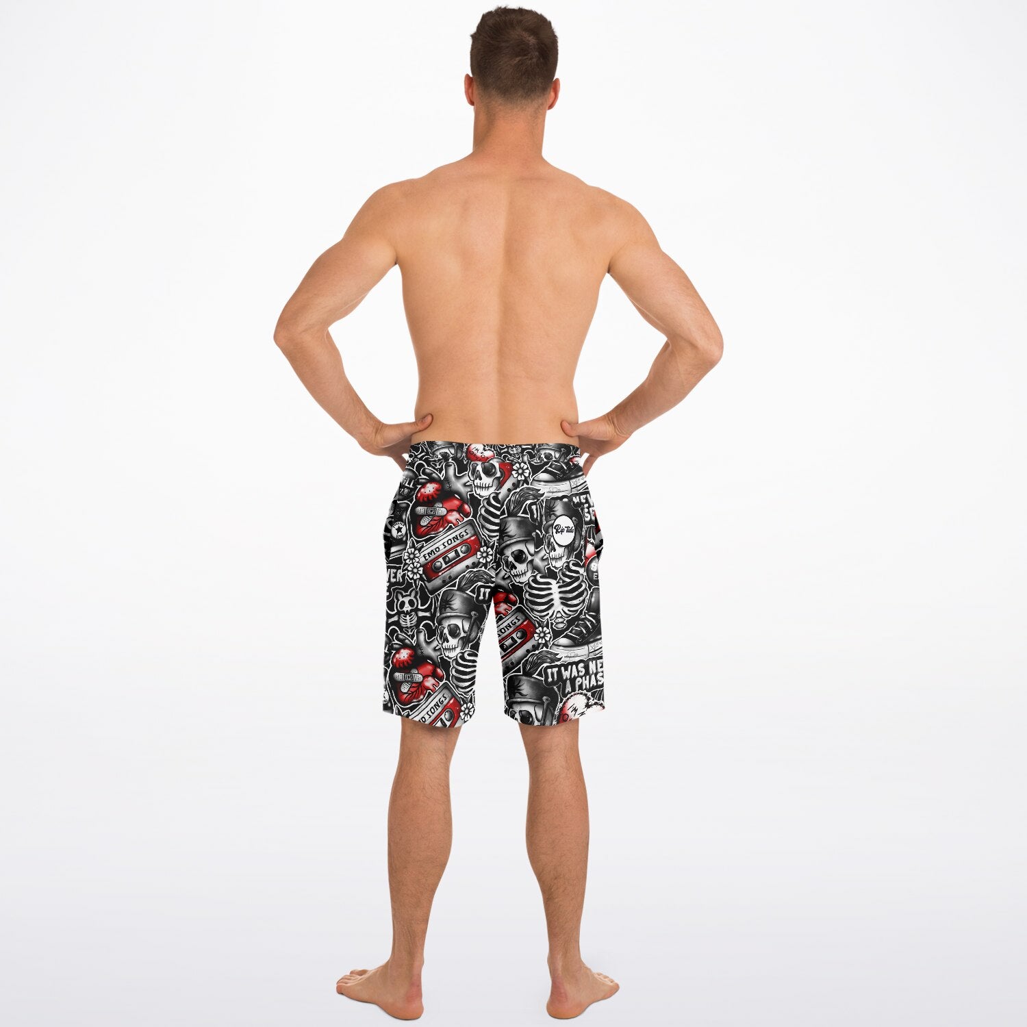 Rip Tide Men's Board Shorts featuring black and white skeleton pattern with red accents, shown from back view on model. Elastic waistband with drawstring, knee-length cut, and mesh-lined pockets visible in the emo-inspired design.