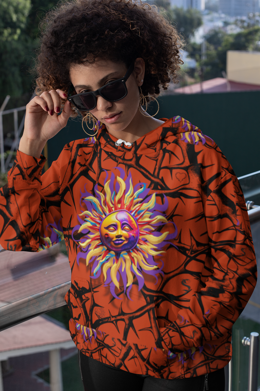 Stylish red hoodie with vibrant sun design and branch pattern, shown outdoors on balcony. Luna Anarchy Red Women's Hoodie features psychedelic purple and yellow sun motif on orange background with black branch details. Womens Hoodie Collection.