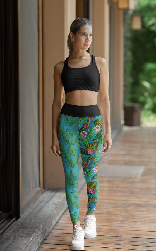 High Waisted Mismatch Core FX Mismatch Leggings - Tropicana shown on athletic figure wearing black sports bra, featuring vibrant tropical print with green palm leaves and colorful flowers, paired with white sneakers in outdoor setting.