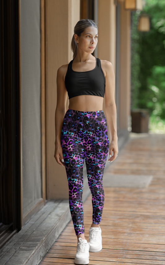 High Waisted Core FX Mismatch Leggings in Futuristic Leopard print shown styled with black sports bra and white sneakers. Vibrant blue and purple leopard pattern creates bold contrast on athletic leggings, photographed in natural lighting on covered porch setting.