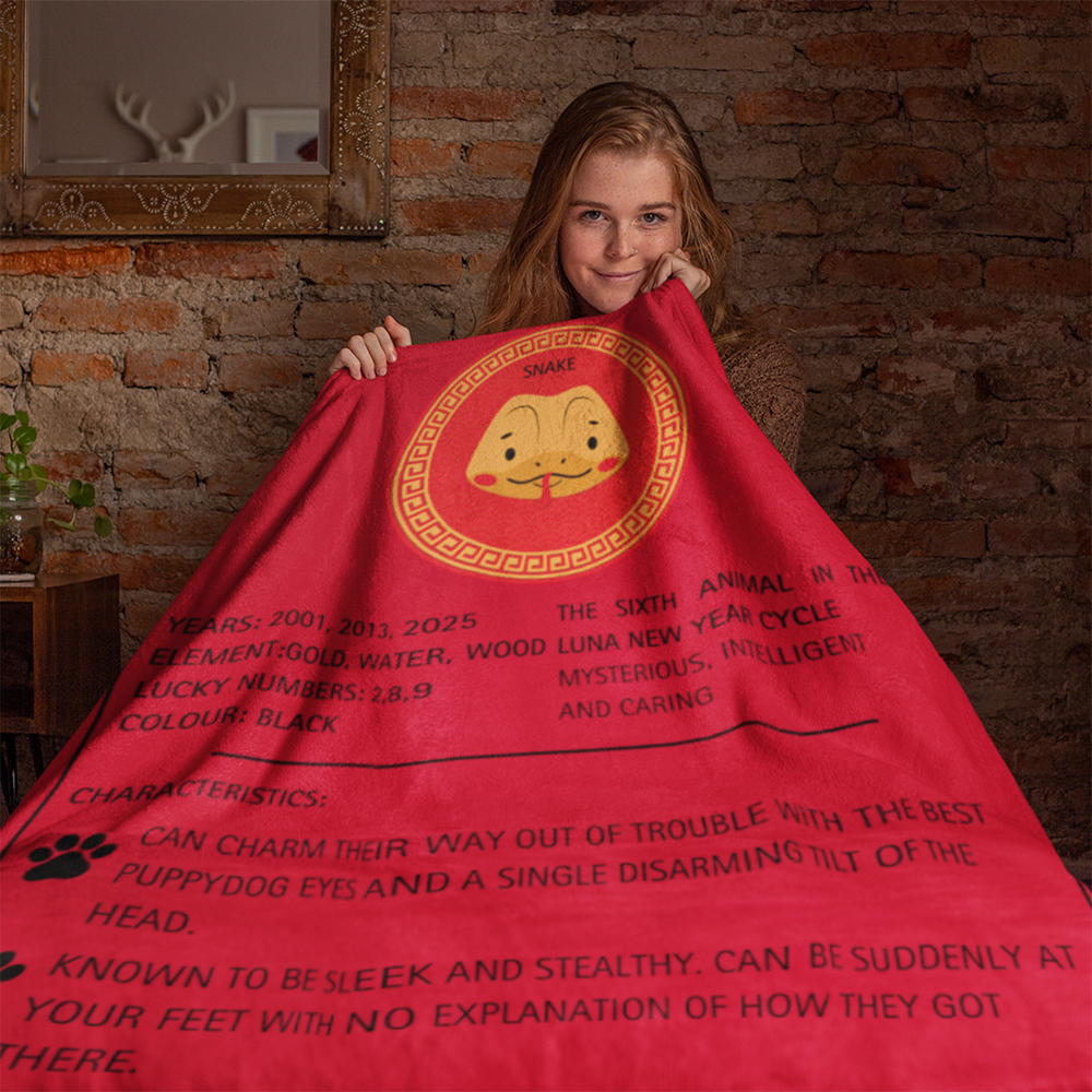 Red sherpa fleece blanket featuring golden Chinese zodiac Snake design with lucky years and characteristics text in black, displayed against exposed brick wall. Luna New Year Zodiac Dog Blanket - Snake from ShitHot Best Sellers, Luna New Year Horoscope Blankets collection.